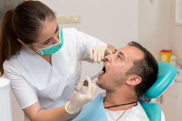 Fototapeta premium Dentist giving an injection of anesthesia to the patient. Young man at the dental clinic