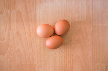 Group of three hen egg on wooden table/ floor background