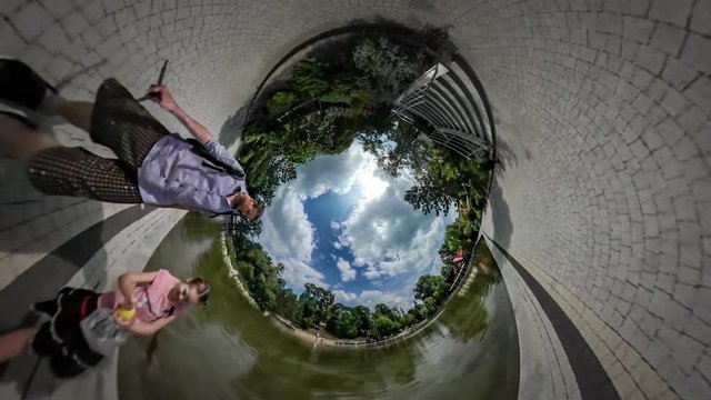 360Vr Video Dad and Kid Play Near Shallow Pond Green Summer Park Paving Tiles Footpath and Benches by the Water Sunny Day Clouds Are Floating on the Sky