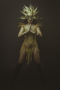 golden mask, brunette goddess dressed in gold lace dress. concep