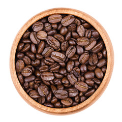Arabica coffee beans in a wooden bowl on white background. Unpulverized roasted brown pits of the coffee cherries. Isolated close up macro photo from above.