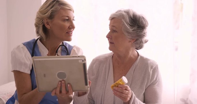 Female doctor showing medical report to senior woman on digital tablet
