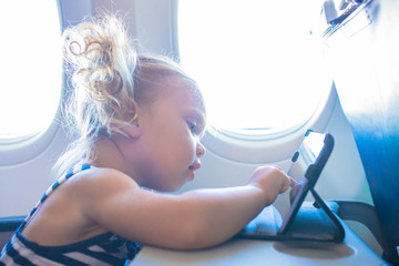 Baby kid using tablet in plane.