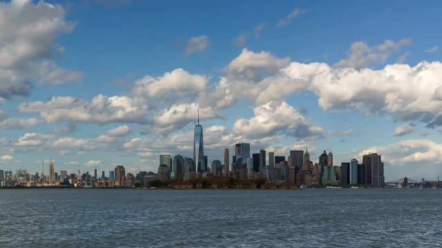 Time lapse of New York City’s Lower Manhattan Financial District skyscrapers and clouds with Ellis Island from New York harbor