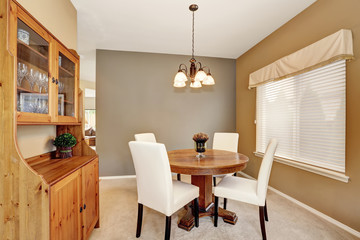Cozy dining room with white chairs and vintage round table.