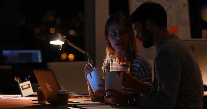 Casual colleagues eating noodles at night