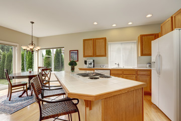 Light wooden kitchen interior with kitchen island and wicker stools