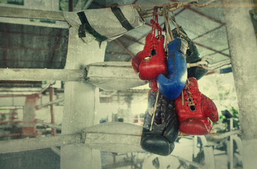 A pair of old Muay Thai boxing gloves hangs on the boxing ring in a slum camp.Vintage effect added...