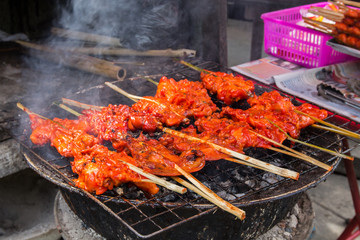 Grilling chicken plugged with bamboo on the tray.