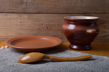 Rustic still life. Clay pot, spoon and plate on linen napkin. Wo