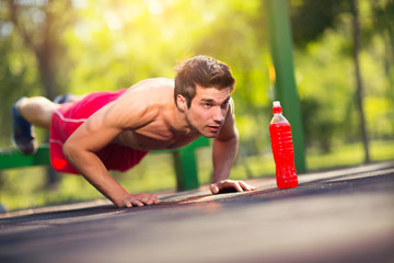 Picture of a young athletic man doing push ups outdoors.