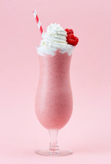 Glass of raspberry milkshake with whipped cream and fresh raspbe