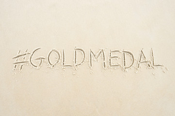 Hashtag social media message for gold medal written in sand on the beach in Rio de Janeiro, Brazil