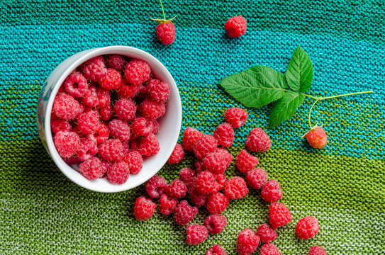 plate bent and ripe raspberries crumbled on linen green cloth