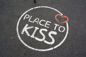 Circle, red heart and text Place to Kiss painted on pavement. Romantic appeal to show intimate feelings towards to lover / spouse and kiss her or him on public space