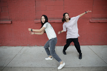 Young Asian woman in city dancing hip hop
