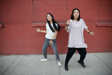 Young Asian woman in city dancing hip hop