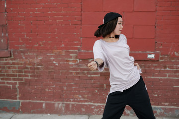Fototapeta na wymiar Young Asian woman in city dancing hip hop