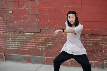 Young Asian woman in city dancing hip hop