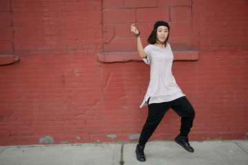 Young Asian woman dancing hip hop in city