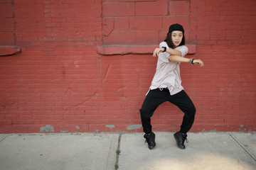 Young Asian woman dancing hip hop in city