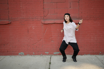 Young Asian woman dancing hip hop in city