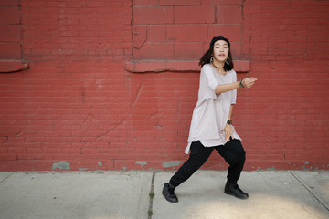 Young Asian woman dancing hip hop in city