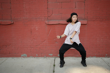 Obraz na płótnie Canvas Young Asian woman dancing hip hop in city