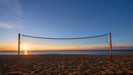 Sillhouette of a volleyball net against sunrise on the beach