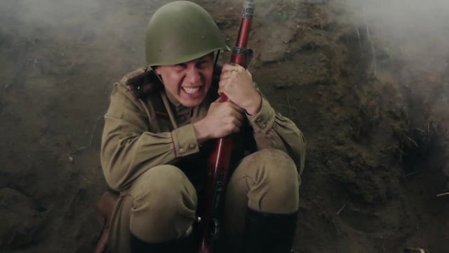 Scared Soviet soldier sits in the trenches during the battle. World War II.