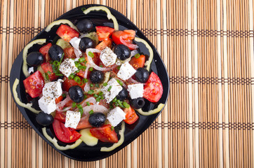Fresh vegetarian salad on a black square plate