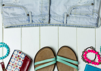 Sandals and denim shorts on a white wooden background