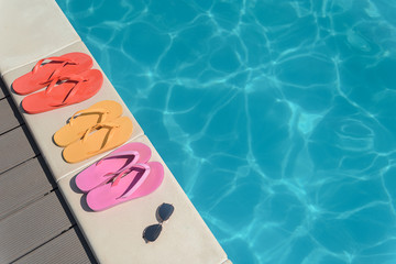 Fototapeta premium Flip flops and sunglasses near water