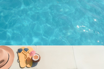 Yellow slippers with drink and cap near water