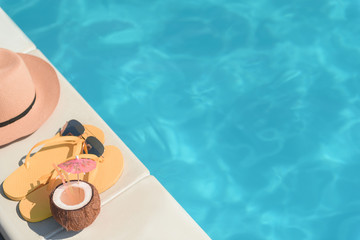 Flip flops with cocktail and sunglasses near pool