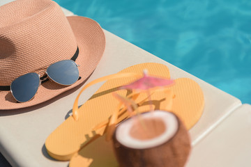 Hat and slippers with beverage near water