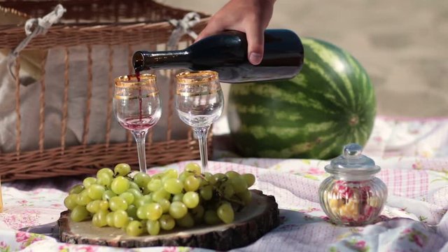 Red wine pouring in crystal glasses on picnic