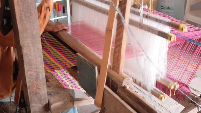 Man working to finish an hammock old mechanism of colorful loom, 4k