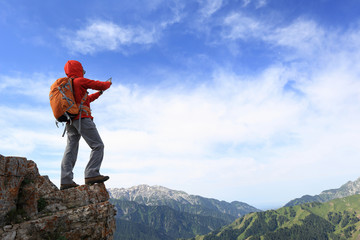 Fototapeta na wymiar successful woman backpacker use digital tablet taking photo on mountain peak cliff