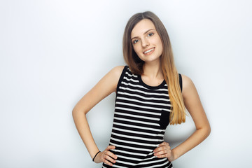 Obraz premium Portrait of happy young beautiful woman in striped shirt posing with hands on hips for model tests against studio background