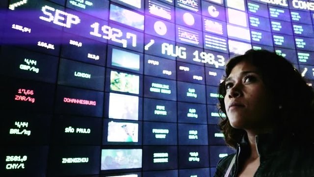 Hispanic woman observing information in a video wall made id flat screens. 4k