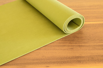 Yoga mat on a wooden background. Equipment for yoga. Concept healthy lifestyle. Lots of copyspace