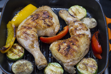 cooking chicken legs and vegetables on the grill pan