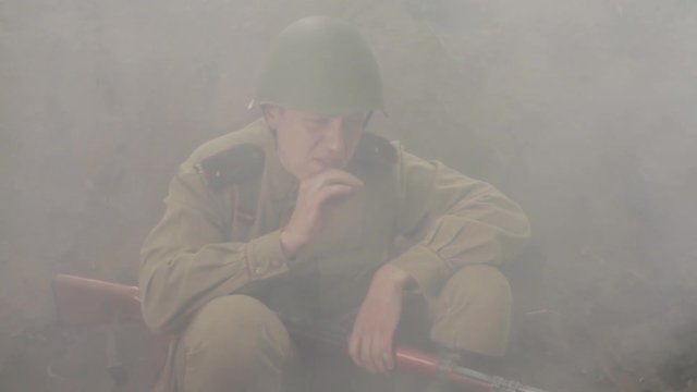 Hardened Soviet soldier sits in the trenches during the battle and smokes.	