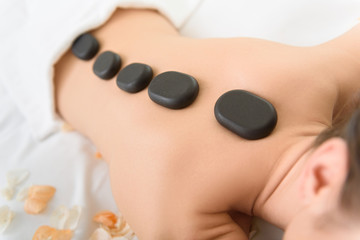 Obraz na płótnie Canvas Young girl getting stones massage at spa