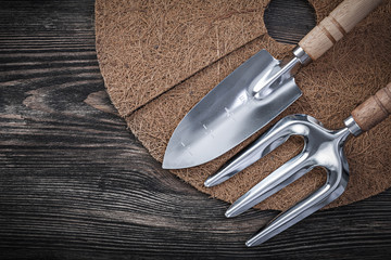 Mulching mat shovel trowel fork on wood board gardening concept