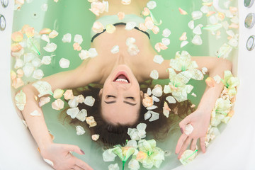 Carefree girl relaxing in bath with flowers
