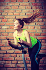 Fototapeta na wymiar Active woman using exercise bike at the gym.