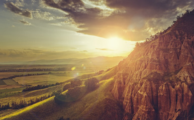 Idyllic scenery with magnificent sunset with lens flare effect over the valley near the Red Ravine (Romanian: Rapa Rosie), a unique natural monument near Sebes city, Alba county, Romania.