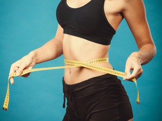Fitness girl measuring her waistline